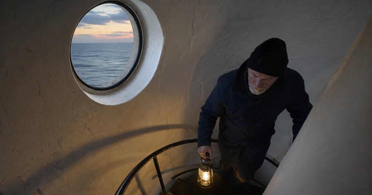 A lighthouse keeper climbing a narrow spiral staircase at dusk with a lantern in hand, the sea visible through a small round window